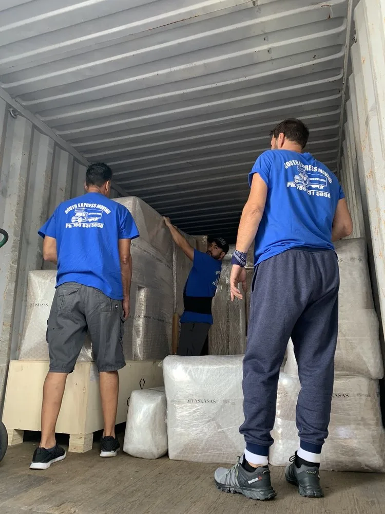 Equipo real de South Express Moving organizando muebles protegidos dentro de un contenedor de carga