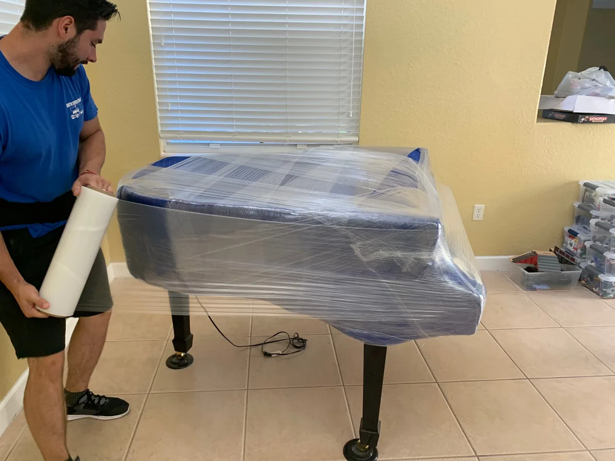 Empleado protegiendo un piano con plástico para envoltura antes del transporte